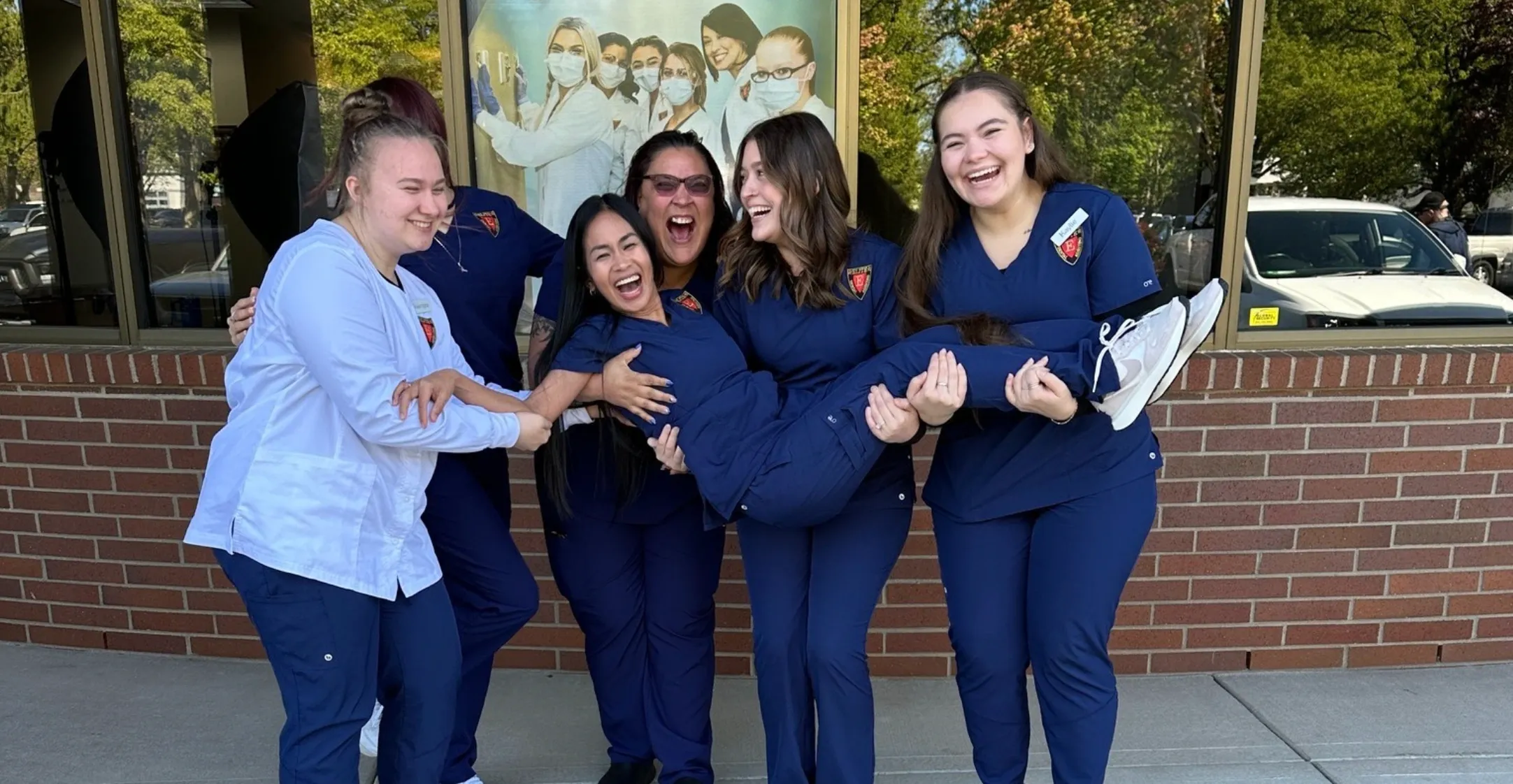 Group of women in blue uniforms laughing.